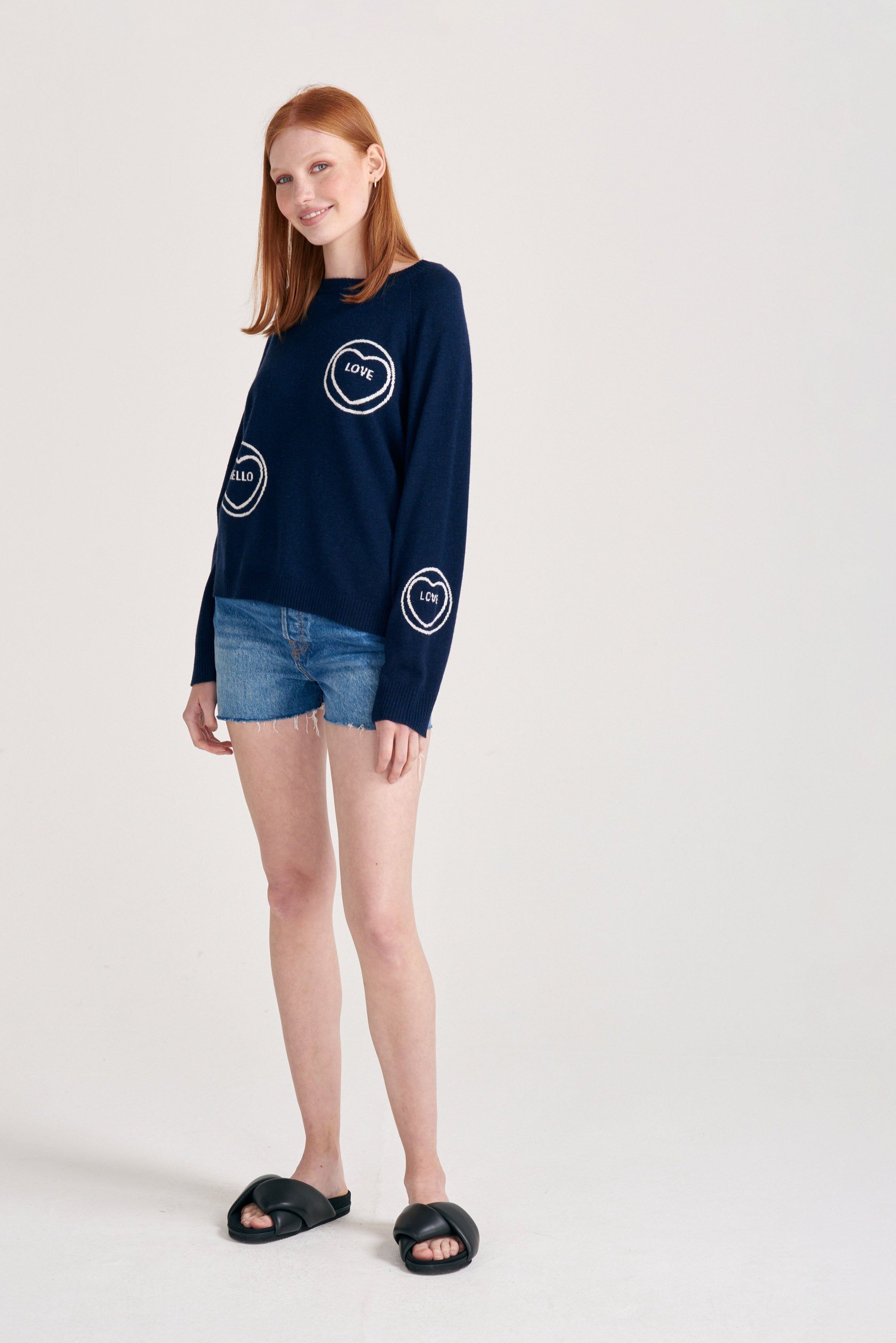 Red haired female model wearing Jumper1234 navy cashmere and wool mix crew neck sweatshirt style jumper with all over cream love hearts intarsia