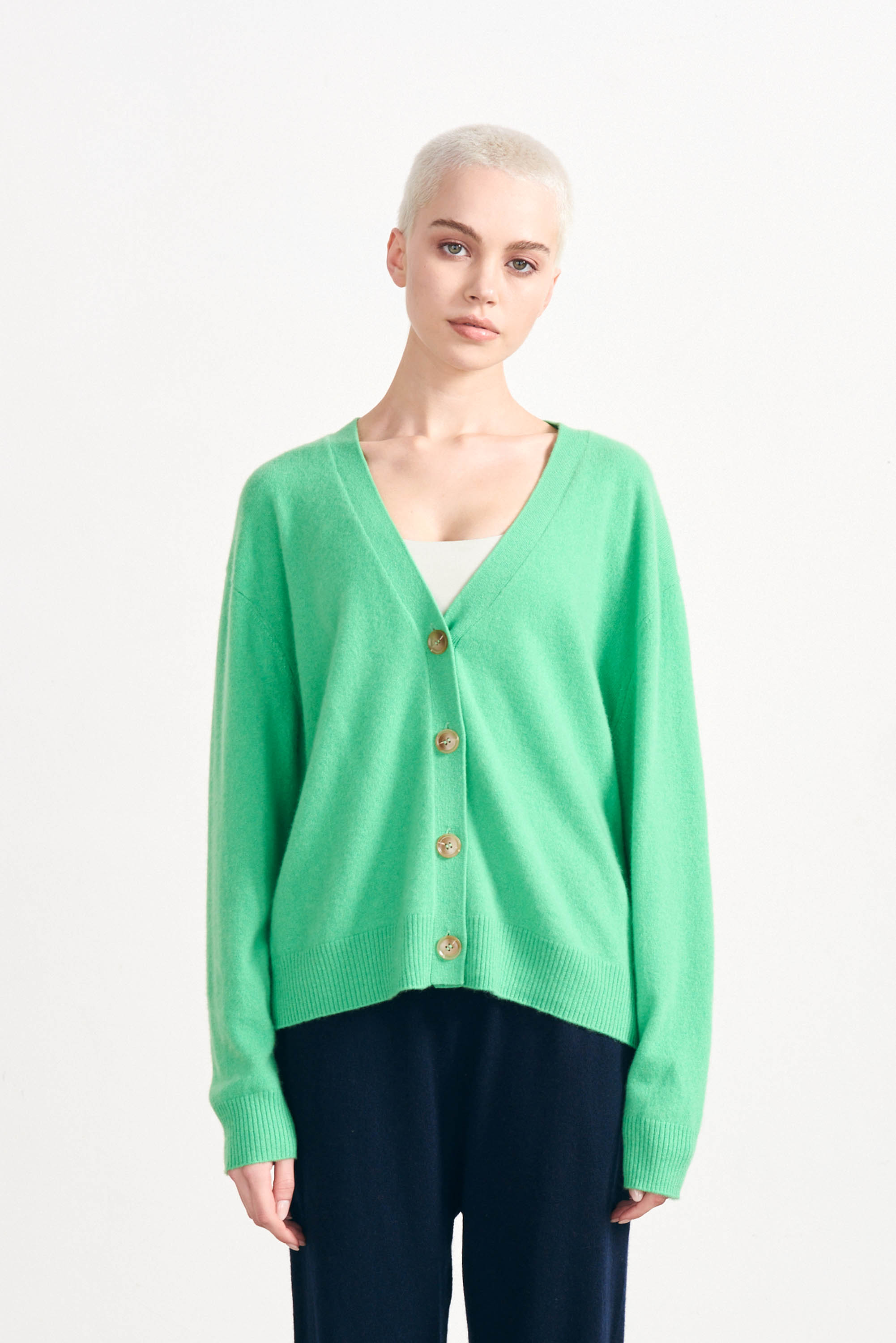 Blonde female model wearing Jumper1234 Bright green cashmere vee neck cardigan with pink love heart 'hello' intarsia on the back