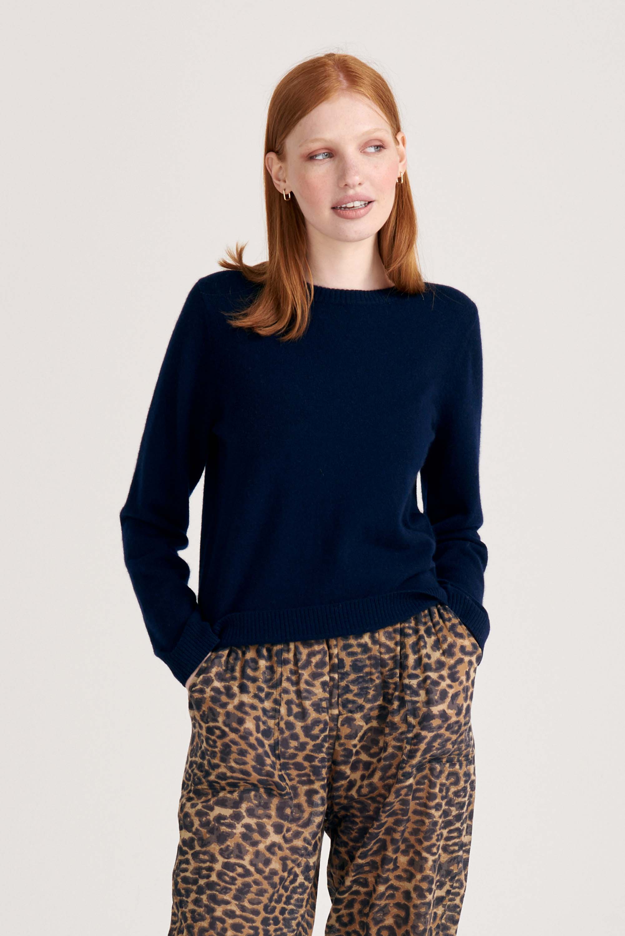 Red haired female model wearing Jumper1234 Navy cashmere crew neck jumper with red love heart intarsia elbow patches