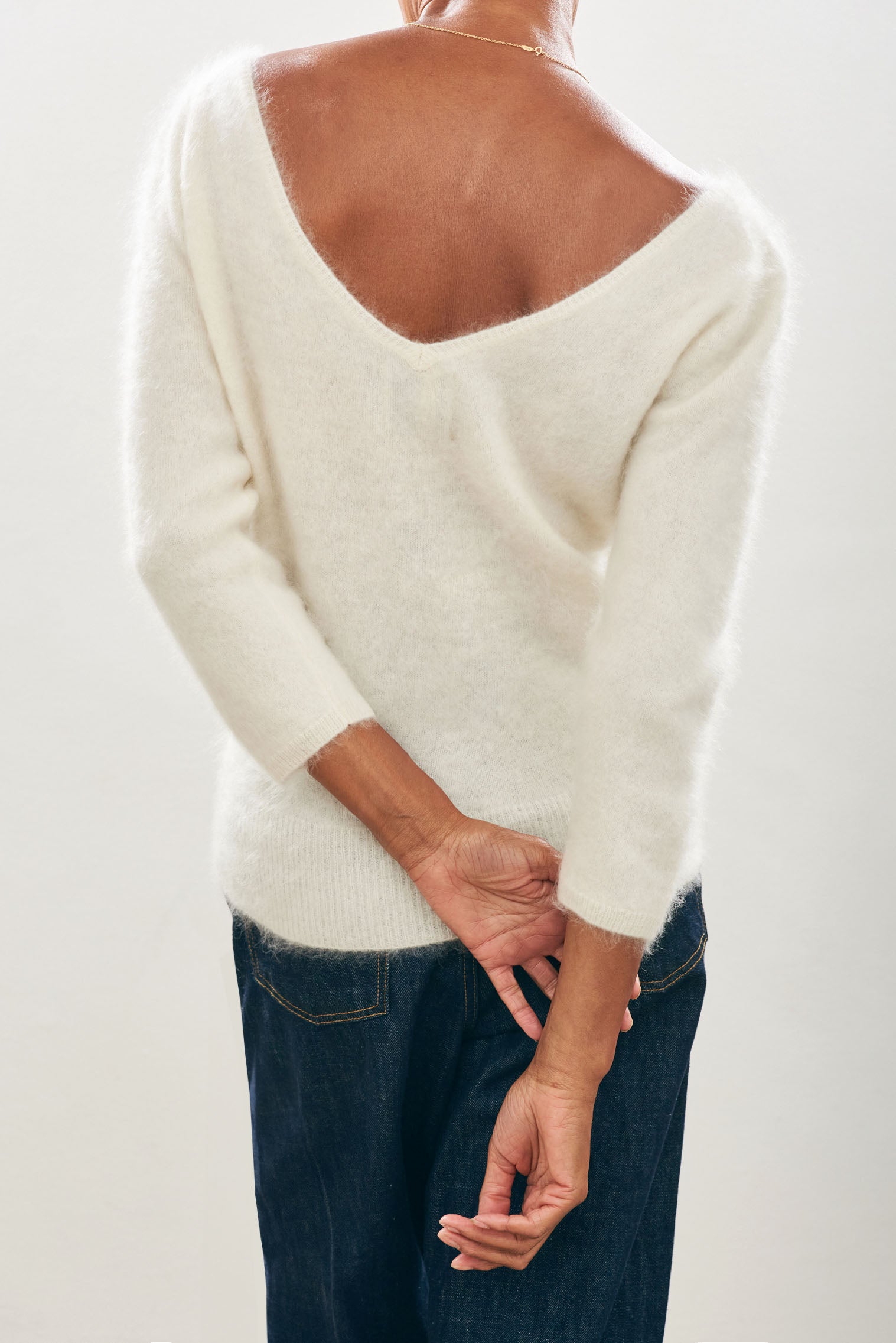 Female model wearing Jumper1234 cream brushed cashmere crew with front and back vee and 3/4 length sleeves facing away from the camera