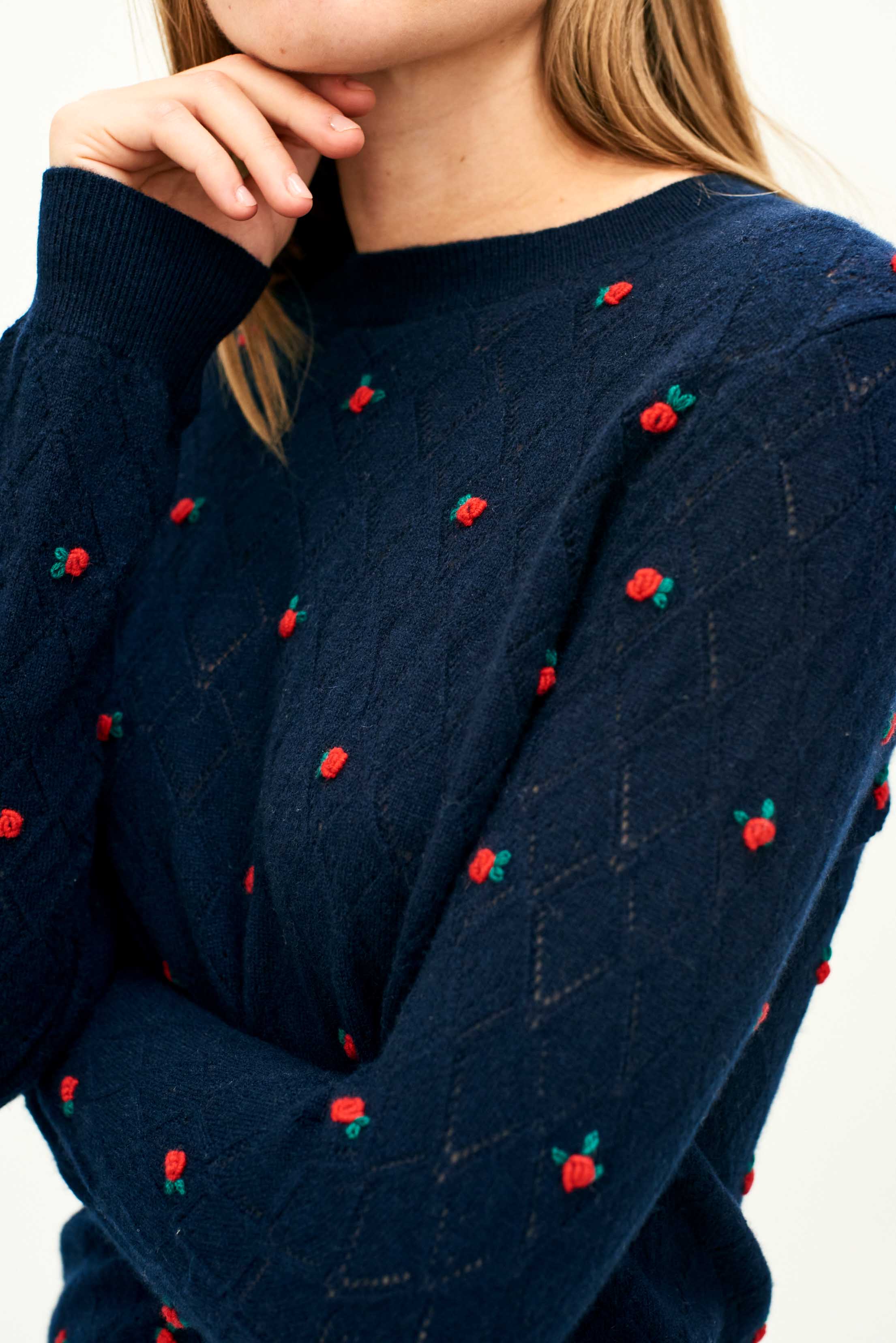 Female model wearing Jumper 1234 Cashmere navy pointelle crew neck with all over little red 3d flowers. Close up