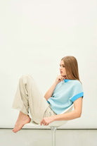 Female model wearing Jumper 1234 Oversize cashmere and wool tank in aqua with silver lurex running through the birdseye texture and contrast darker aqua ribs
