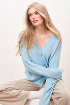 Female model wearing Jumper 1234 Oversize cashmere and wool cardigan in aqua with silver lurex running through the birdseye texture and contrast darker aqua ribs