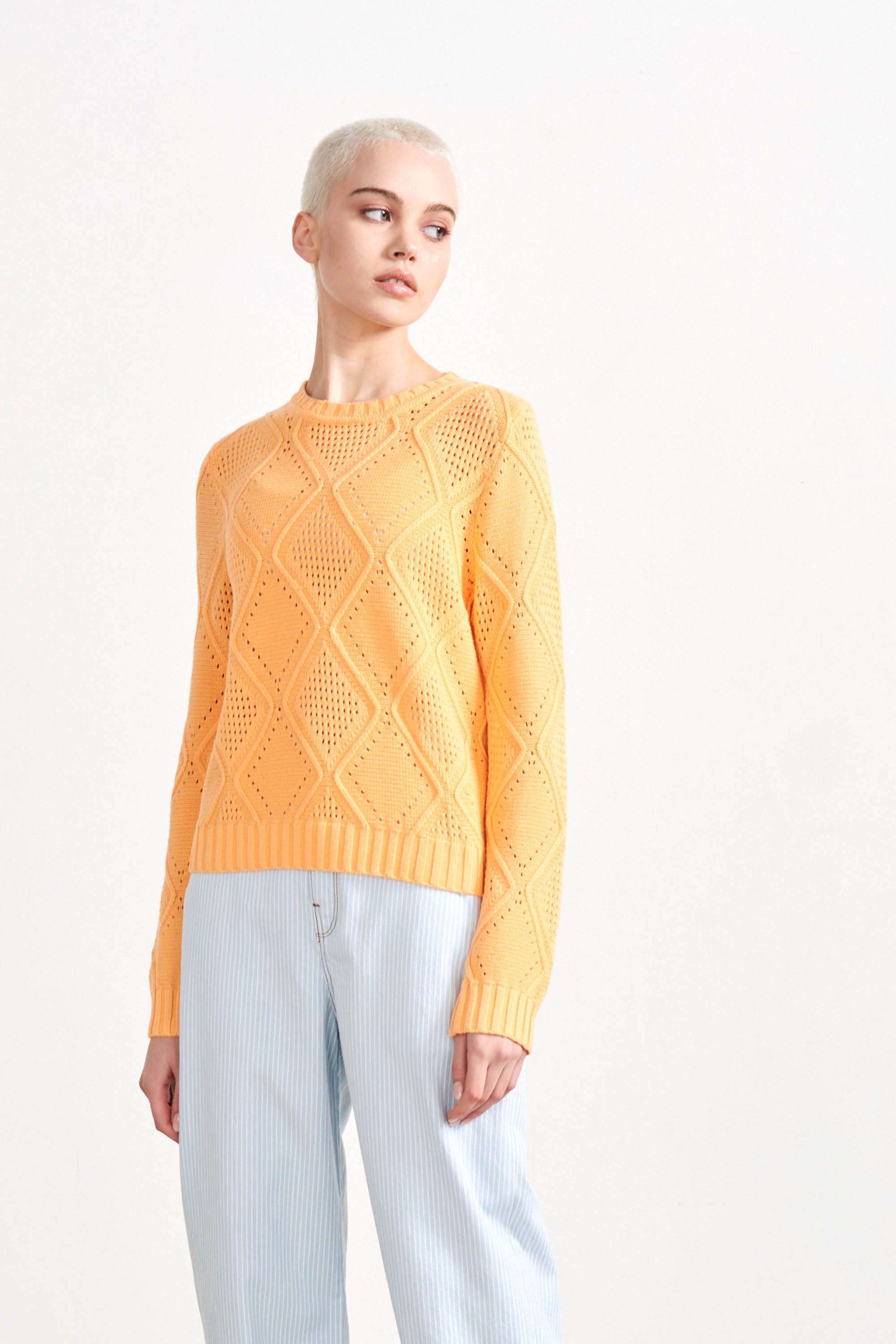 Blonde female model wearing Jumper1234 Apricot cotton crew neck jumper with a diamond texture stitch pattern