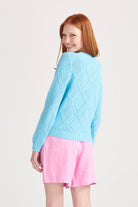 Red haired female model wearing Jumper1234 Opal cotton crew neck jumper with a diamond texture stitch pattern facing away from the camera