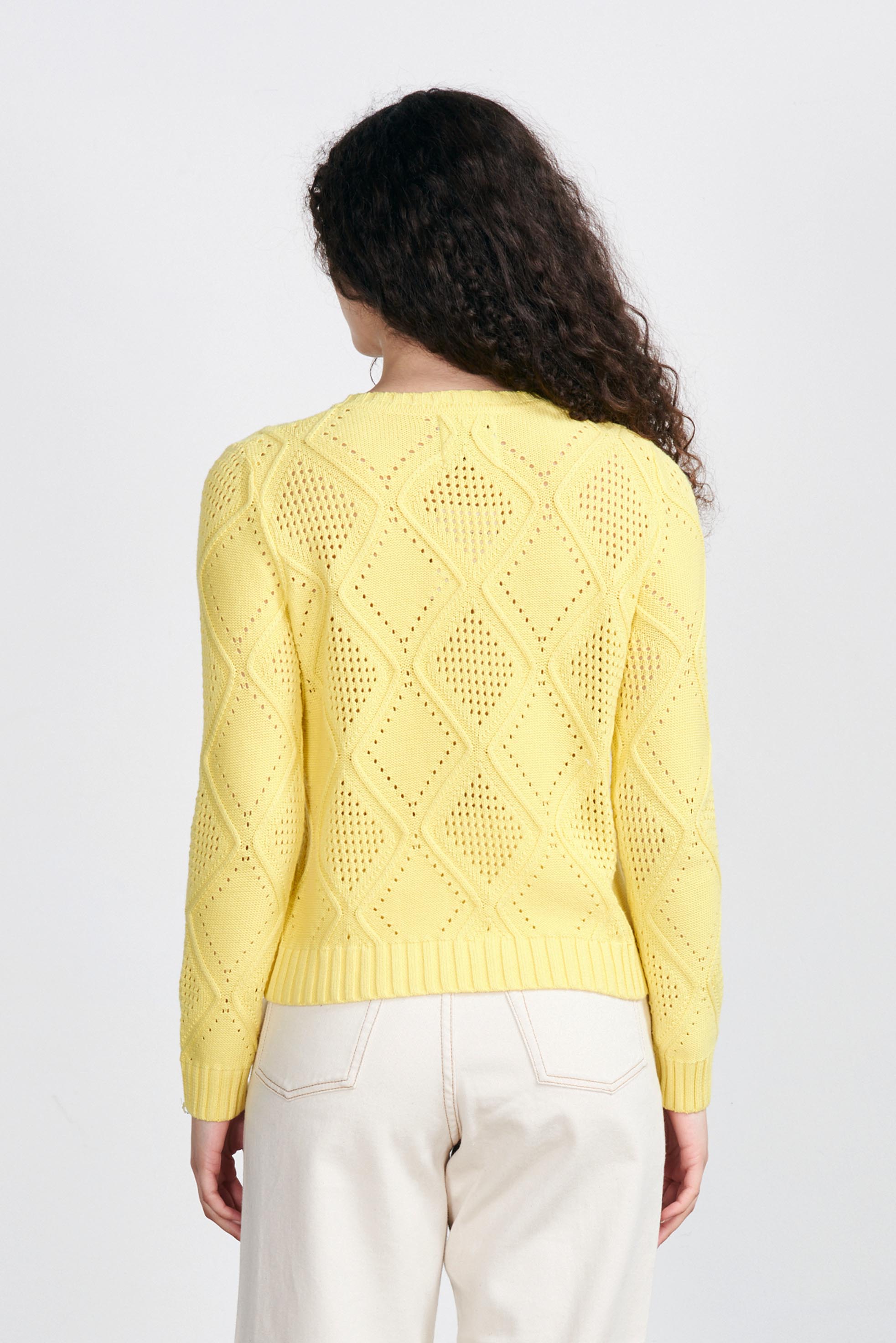 Brown haired female model wearing Jumper1234 Yellow cotton crew neck jumper with a diamond texture stitch pattern facing away from the camera