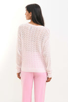 Brown haired female model wearing Jumper1234 pale pink lightweight merino "Lace Vee" facing away from the camera