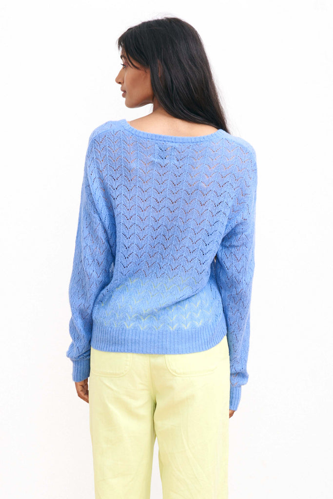 Brown haired female model wearing Jumper1234 blue lightweight merino "Lace Vee" facing away from the camera