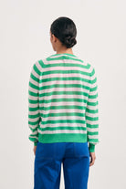 Brown haired female model wearing Jumper1234 bright green and pale pink lightweight merino "Stripe crew" facing away from the camera