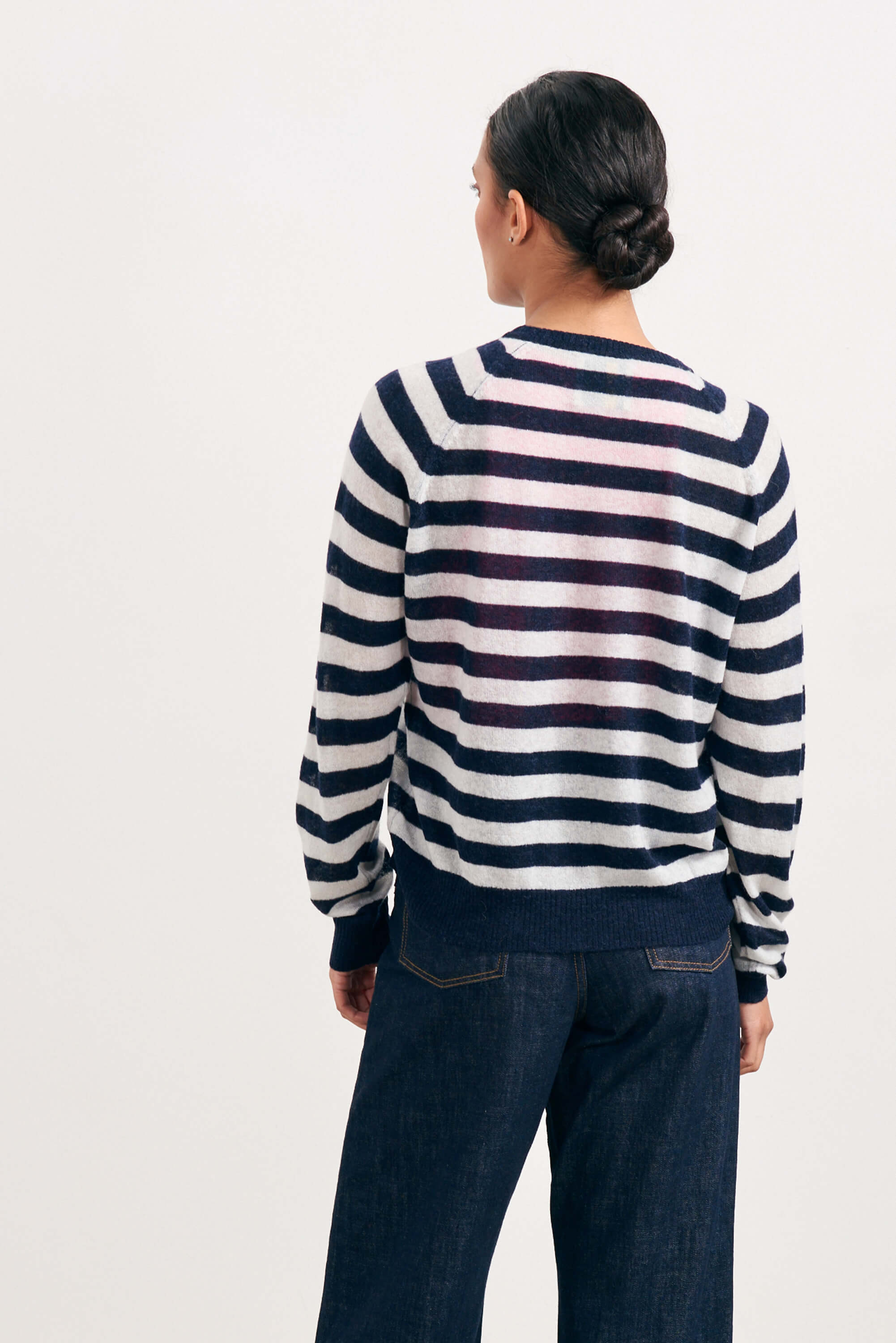 Brown haired female model wearing Jumper1234 bright navy and cream lightweight merino "Stripe crew" facing away from the camera