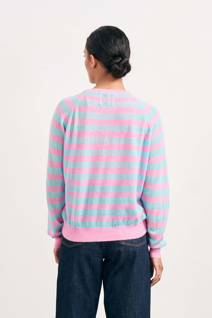 Brown haired female model wearing Jumper1234 bright pink and turquoise lightweight merino "Stripe crew" facing away from the camera