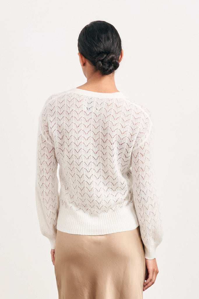 Brown haired female model wearing Jumper1234 cream lightweight merino "Lace cardigan" facing away from the camera