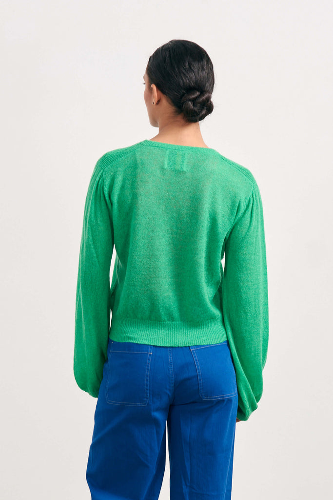 Brown haired female model wearing Jumper1234 bright green lightweight merino "Balloon Sleeve crew" facing away from the camera