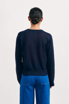 Brown haired female model wearing Jumper1234 navy lightweight merino "Balloon Sleeve crew" facing away from the camera