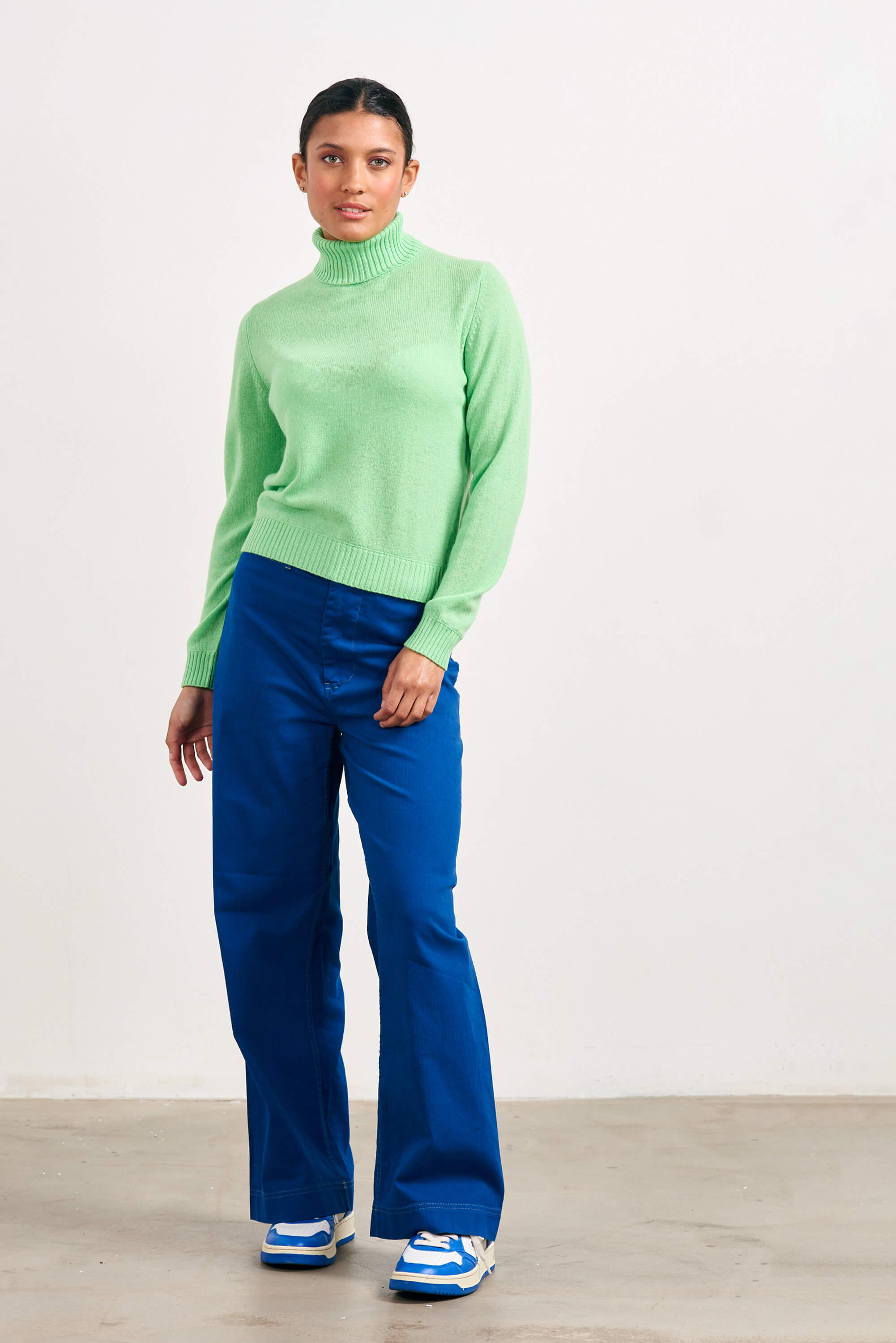 Brown haired female model wearing Jumper1234 lightweight cashmere roll neck in apple green 