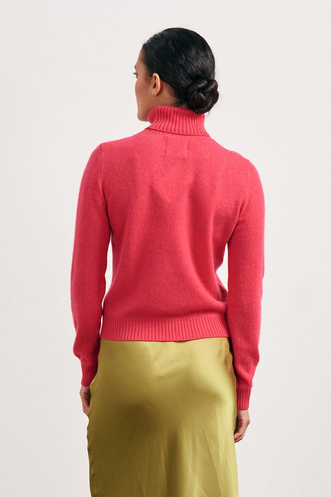 Brown haired female model wearing Jumper1234 lightweight cashmere roll neck in cherry facing away from the camera