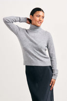 Brown haired female model wearing Jumper1234 lightweight cashmere roll neck in mid grey