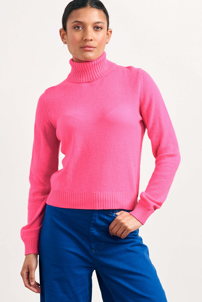 Brown haired female model wearing Jumper1234 lightweight cashmere roll neck in neon pink