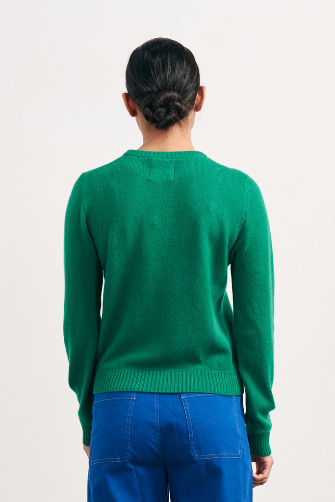 Brown haired female model wearing Jumper1234 lightweight cashmere crew neck in grass green facing away from the camera