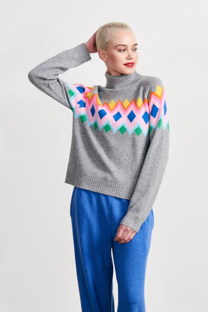 Blonde female model wearing Jumper 1234 mid grey heavier weight cashmere roll neck, with an intarsia Fairisle panel back and front in a fabulous combination of bright colours
