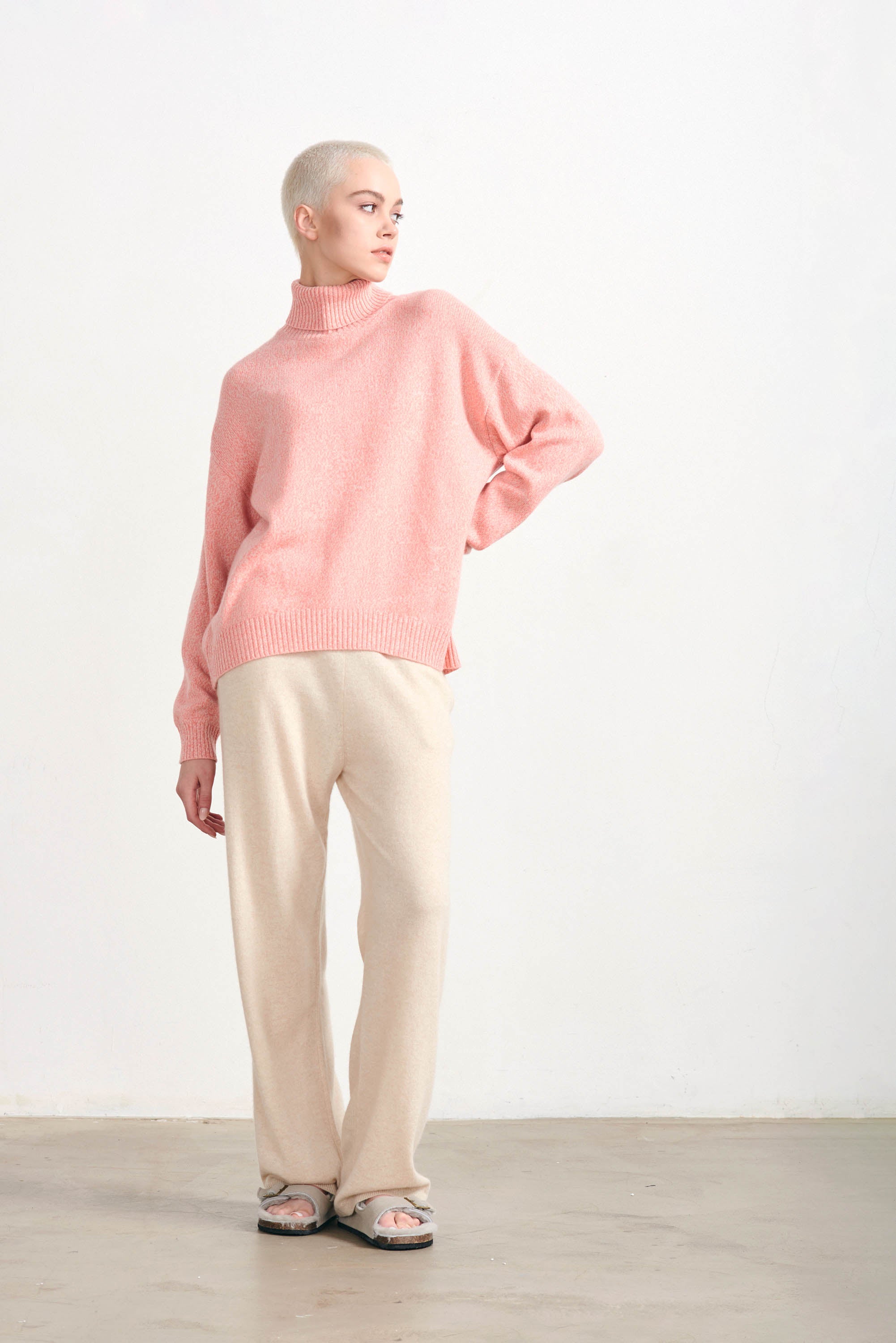 Blonde female model wearing Jumper 1234 cashmere and wool heavier weight oversized roll neck jumper in coral marl