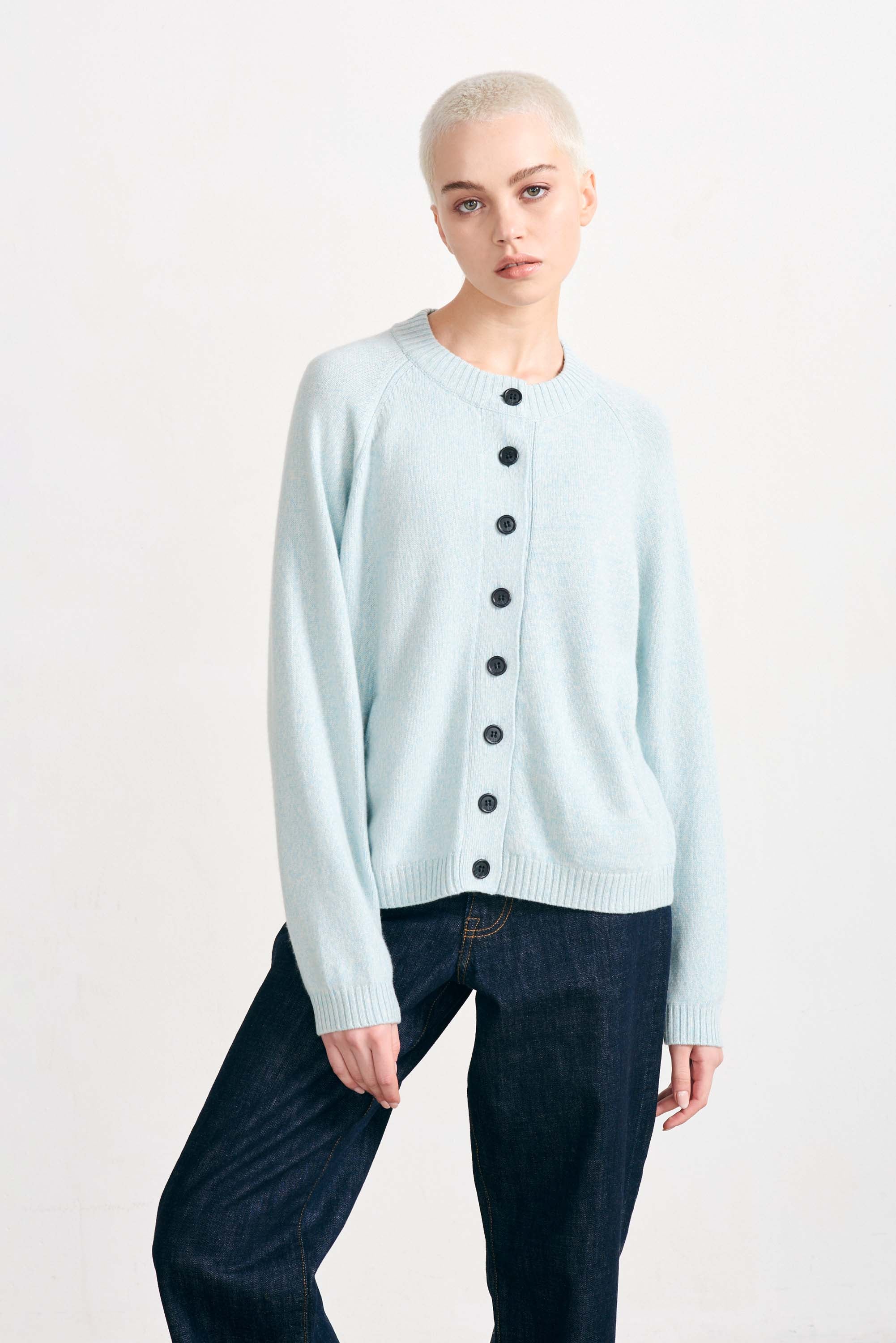 Blonde female model wearing Jumper 1234 cashmere and wool heavier weight round neck cardigan in ice blue marl