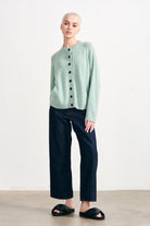 Blonde female model wearing Jumper 1234 cashmere and wool heavier weight round neck cardigan in sage green marl