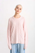Blonde female model wearing Jumper 1234 cashmere and wool heavier weight Aran crew neck jumper in pale pink marl