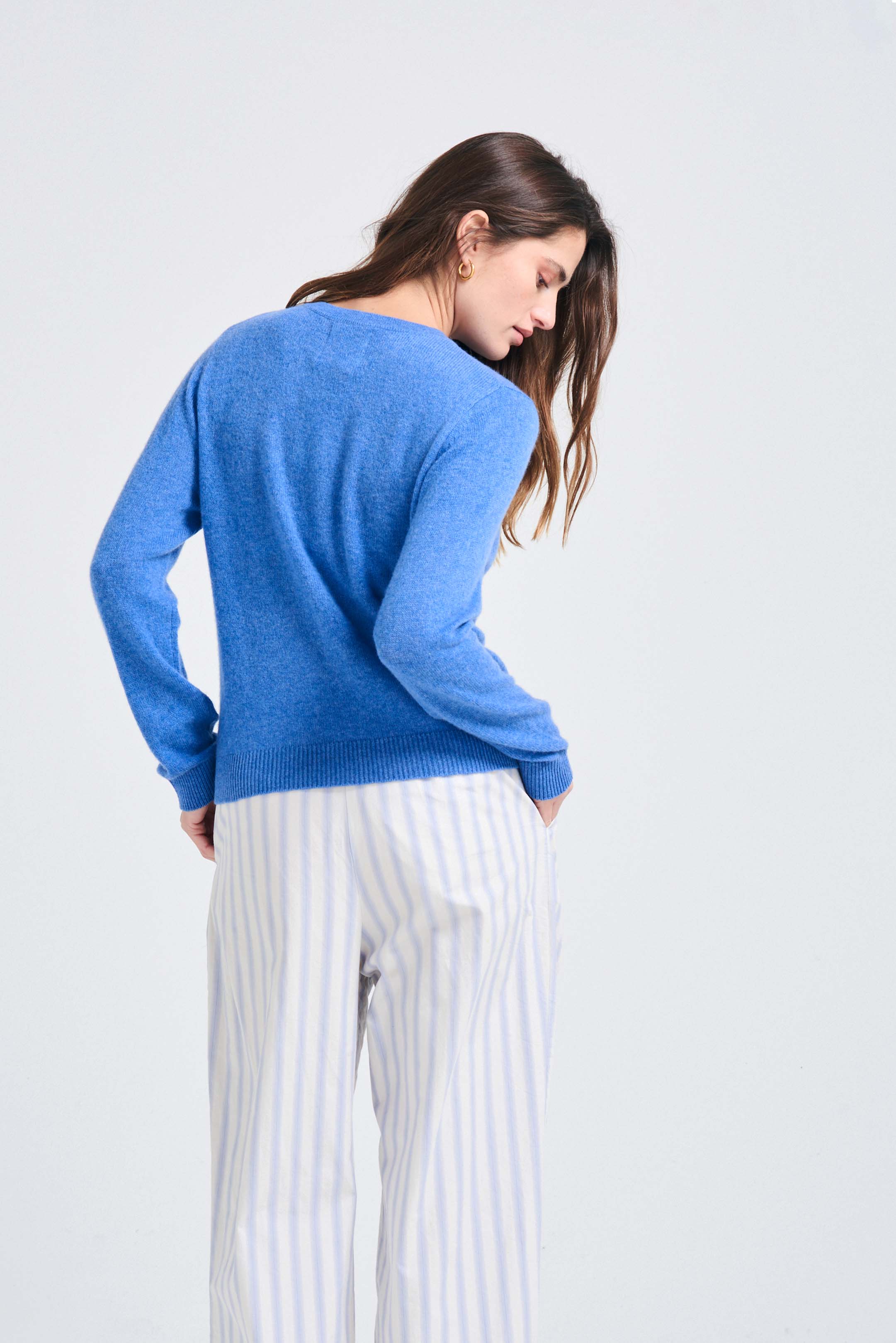 Brown haired female model wearing Jumper1234 Periwinkle blue lighter weight crew neck cashmere jumper facing away from the camera
