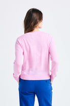 Brown haired female model wearing Jumper1234 Rose pink lighter weight crew neck cashmere jumper facing away from the camera
