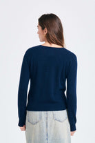 Brown haired female model wearing Jumper1234 Navy lighter weight vee neck cashmere jumper facing away from the camera