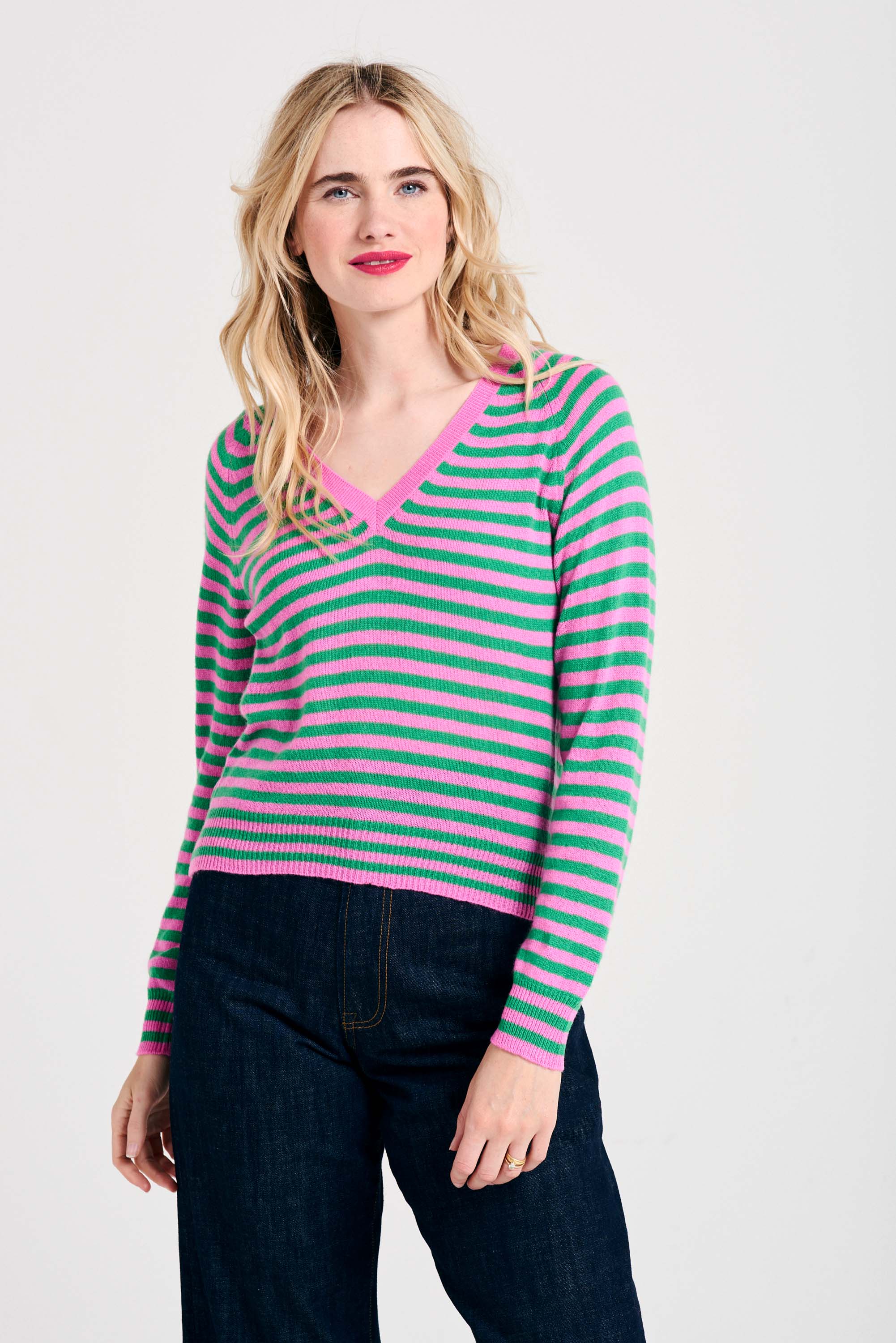 Blonde female model wearing Jumper1234 Peony and bright green narrow stripe lighter weight vee neck cashmere jumper