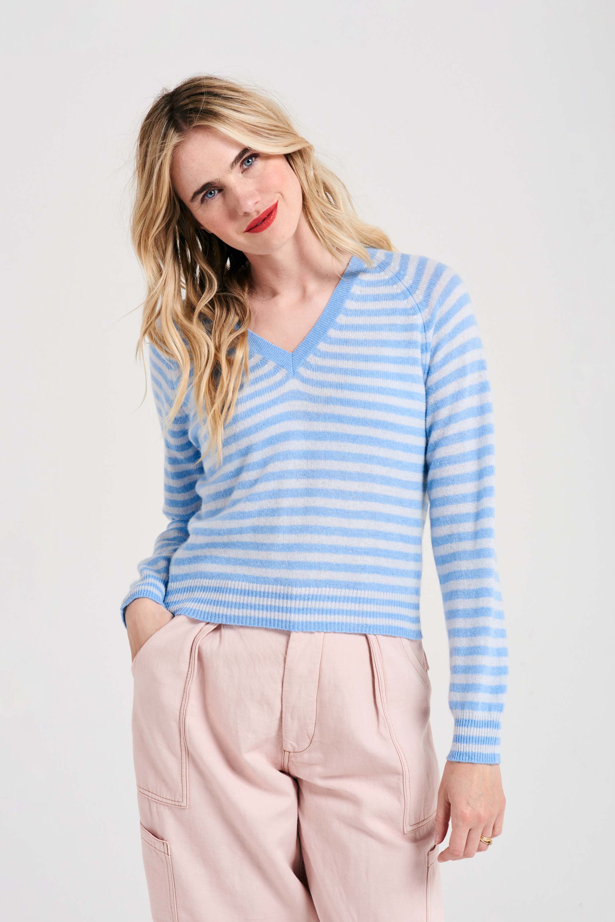 Blonde female model wearing Jumper1234 Wedgewood and cement narrow stripe lighter weight vee neck cashmere jumper
