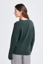 Brown haired female model wearing Jumper1234 Oversize cashmere vee neck cardigan in khaki facing away from the camera