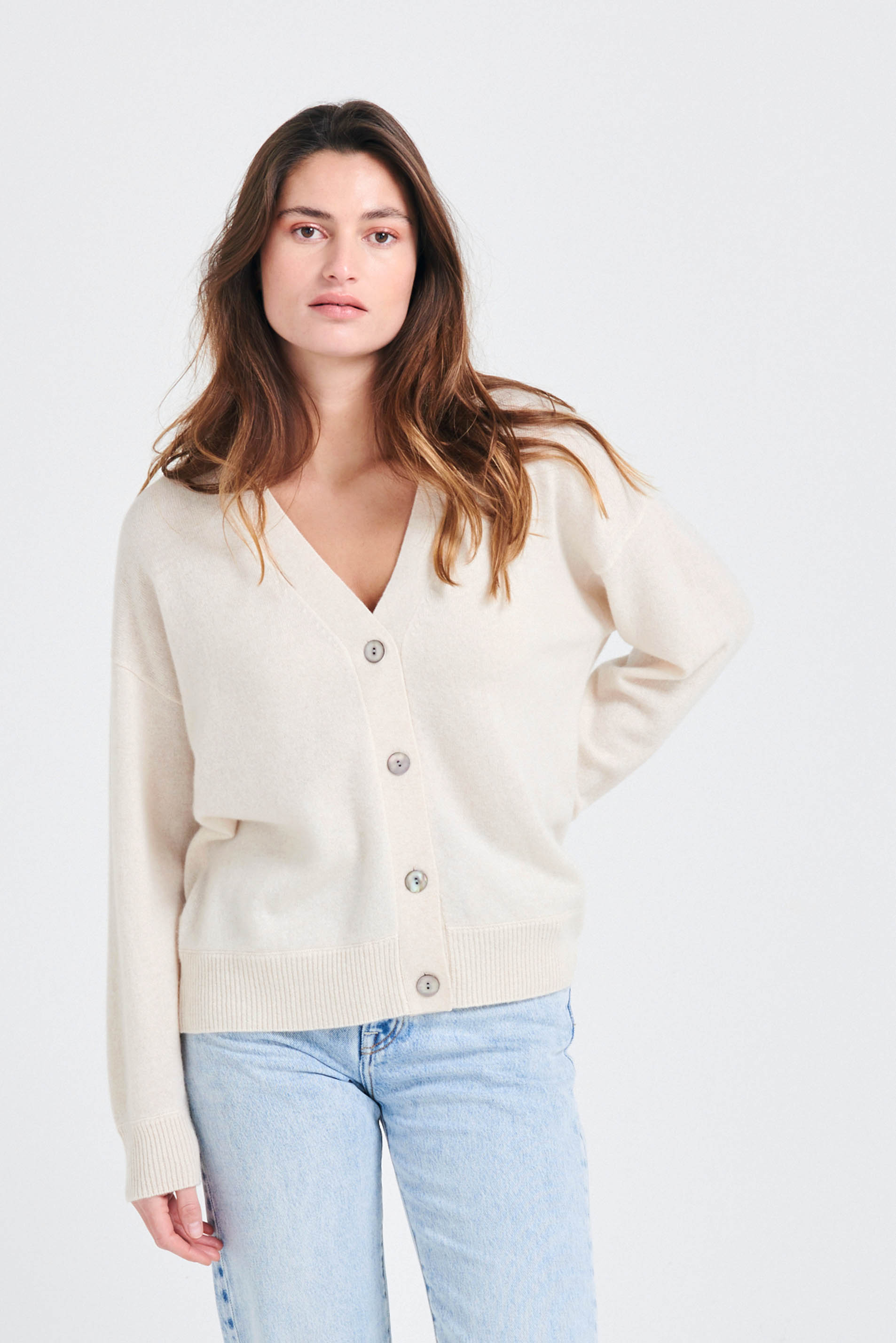 Brown haired female model wearing Jumper1234 Oversize cashmere vee neck cardigan in oatmeal
