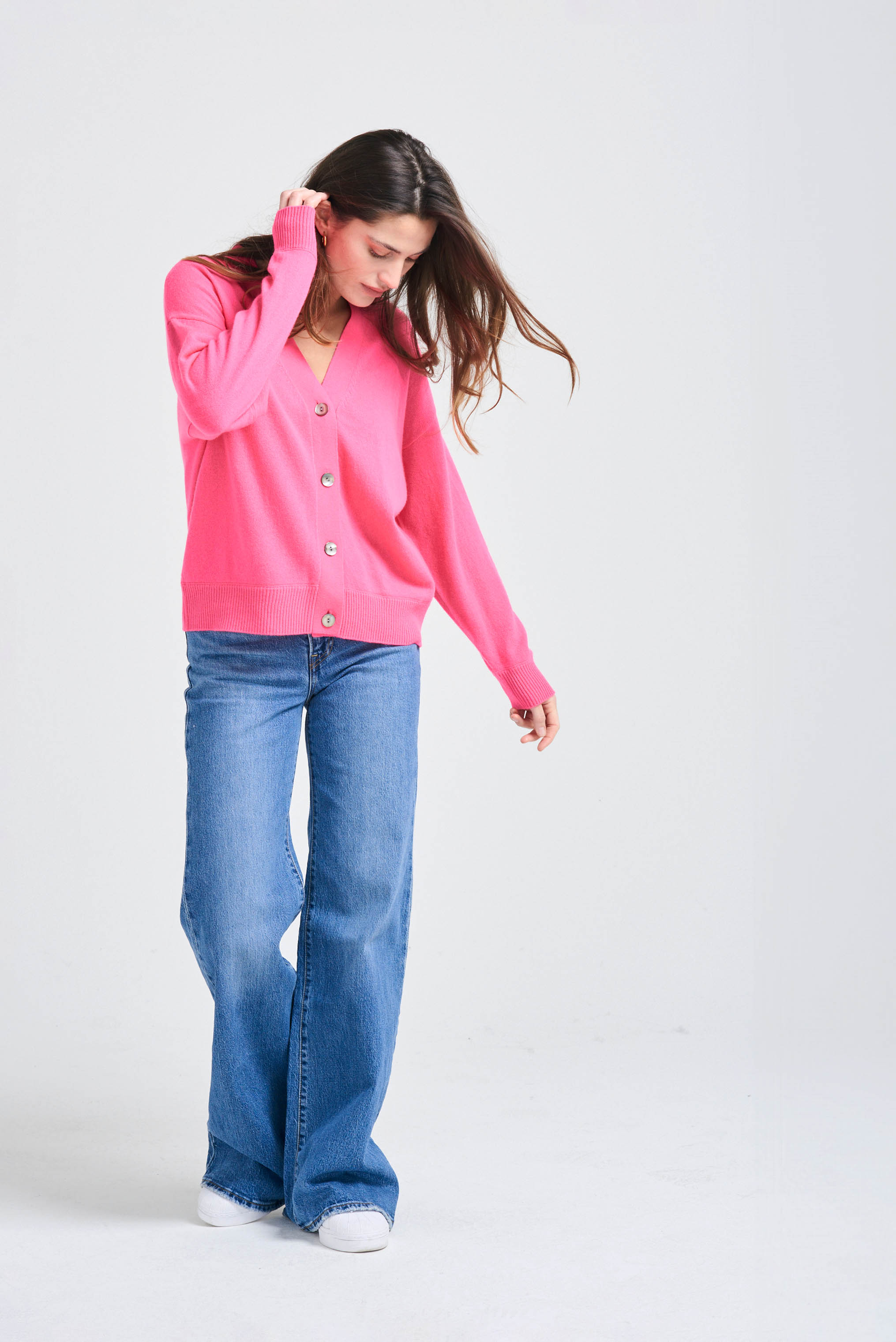 Brown haired female model wearing Jumper1234 Oversize cashmere vee neck cardigan in neon pink