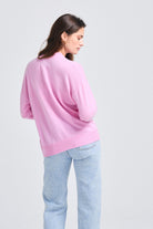 Brown haired female model wearing Jumper1234 Oversize cashmere vee neck cardigan in rose facing away from the camera