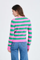 Brown haired female model wearing Jumper1234 Stripe cashmere crew neck jumper in peony and bright green facing away from the camera