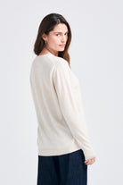 Brown haired female model wearing Jumper1234 Boyfriend fit cashmere crew neck jumper in oatmeal facing away from the camera
