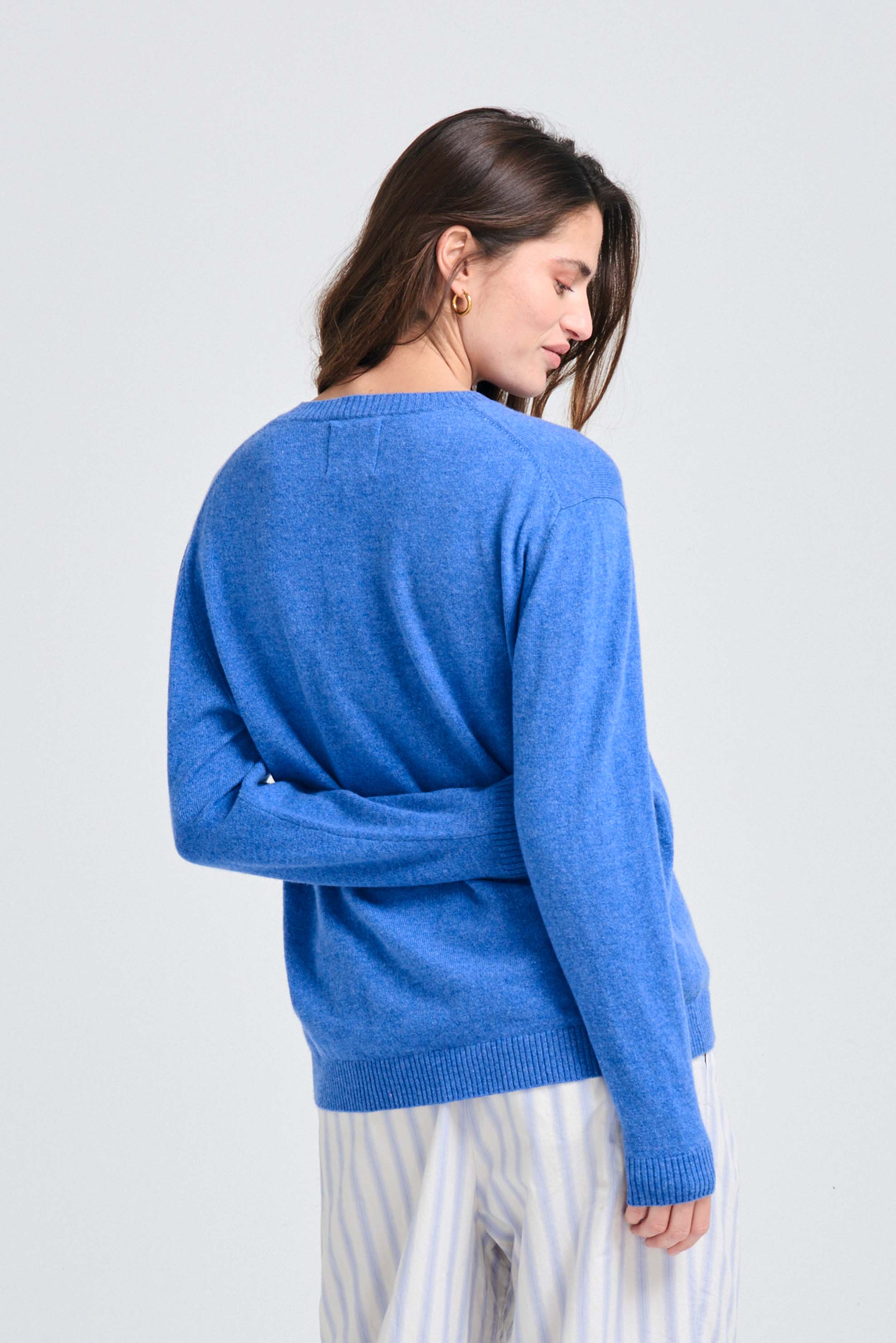 Brown haired female model wearing Jumper1234 Boyfriend fit cashmere crew neck jumper in periwinkle blue facing away from the camera