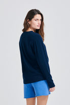 Brown haired female model wearing Jumper1234 Boyfriend fit cashmere crew neck jumper in navy facing away from the camera