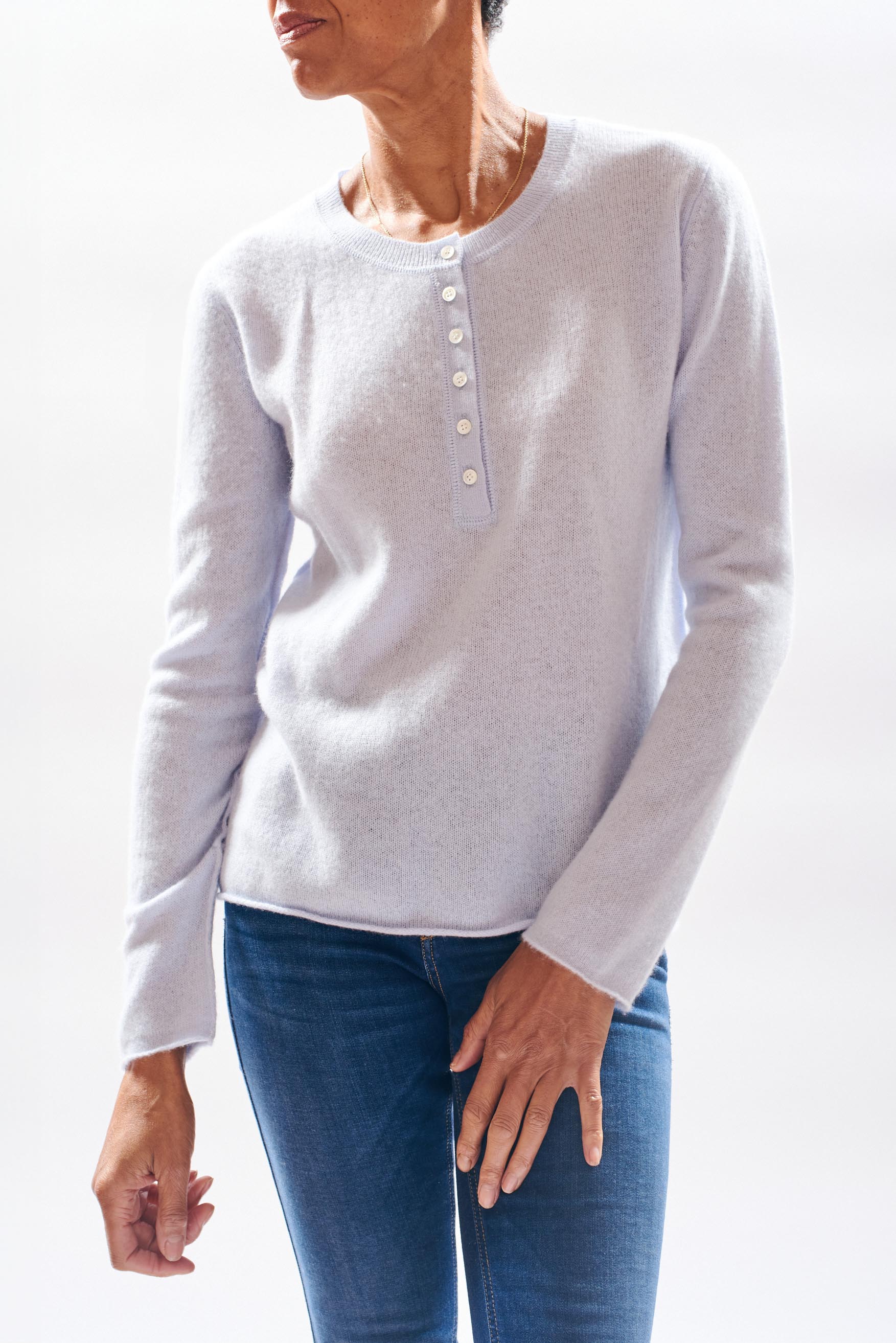 Model wearing Jumper 1234 cashmere henley in pale blue with a contrast gold stitching on the top button