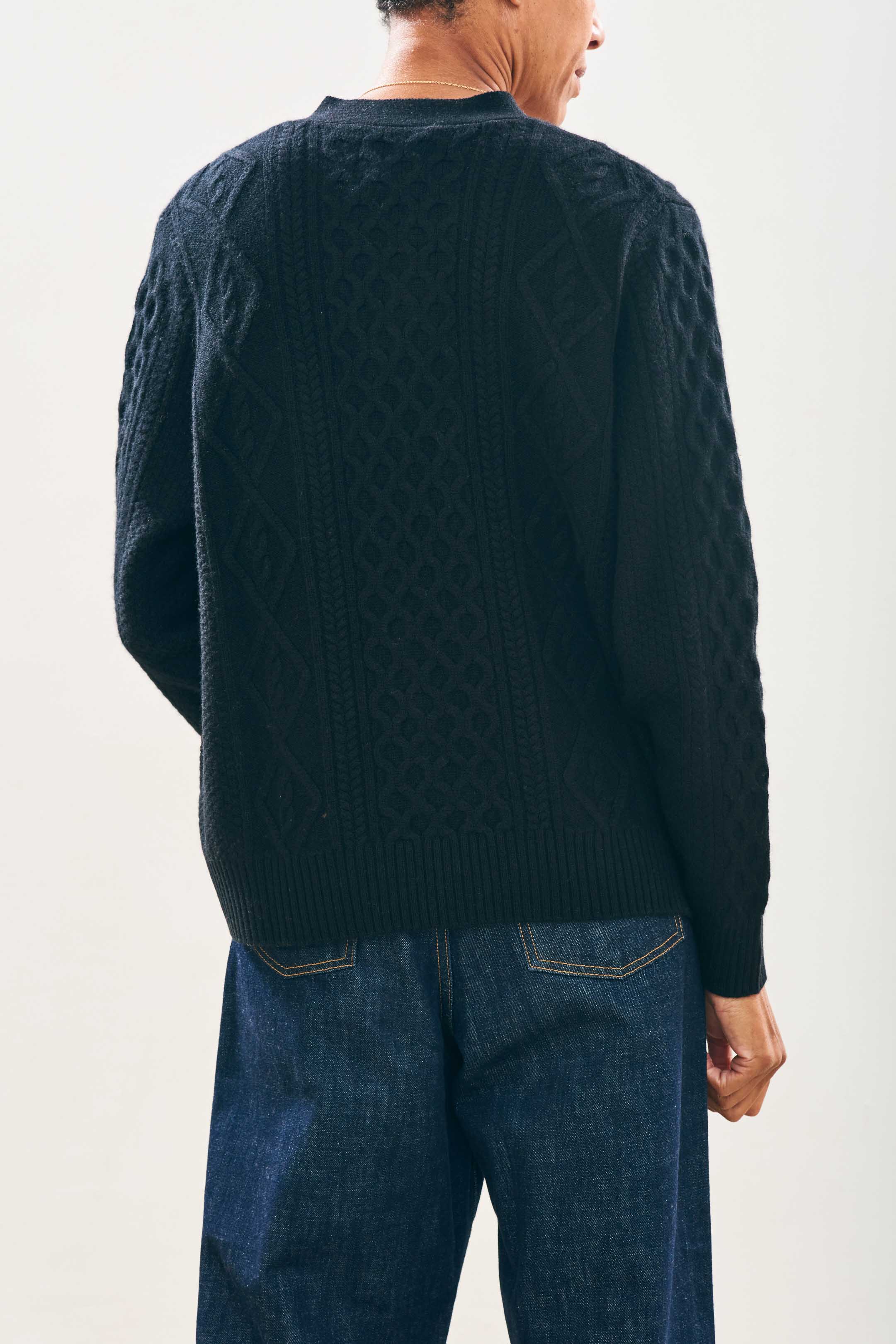 Model wearing Jumper1234 Cashmere Wool Aran Cardigan in Black facing away from the camera