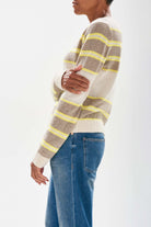 Model standing sideways on wearing Jumper 1234 cashmere oatmeal and organic light brown stripe crew neck cashmere jumper with textured 'hole' details and a little lemon stripes