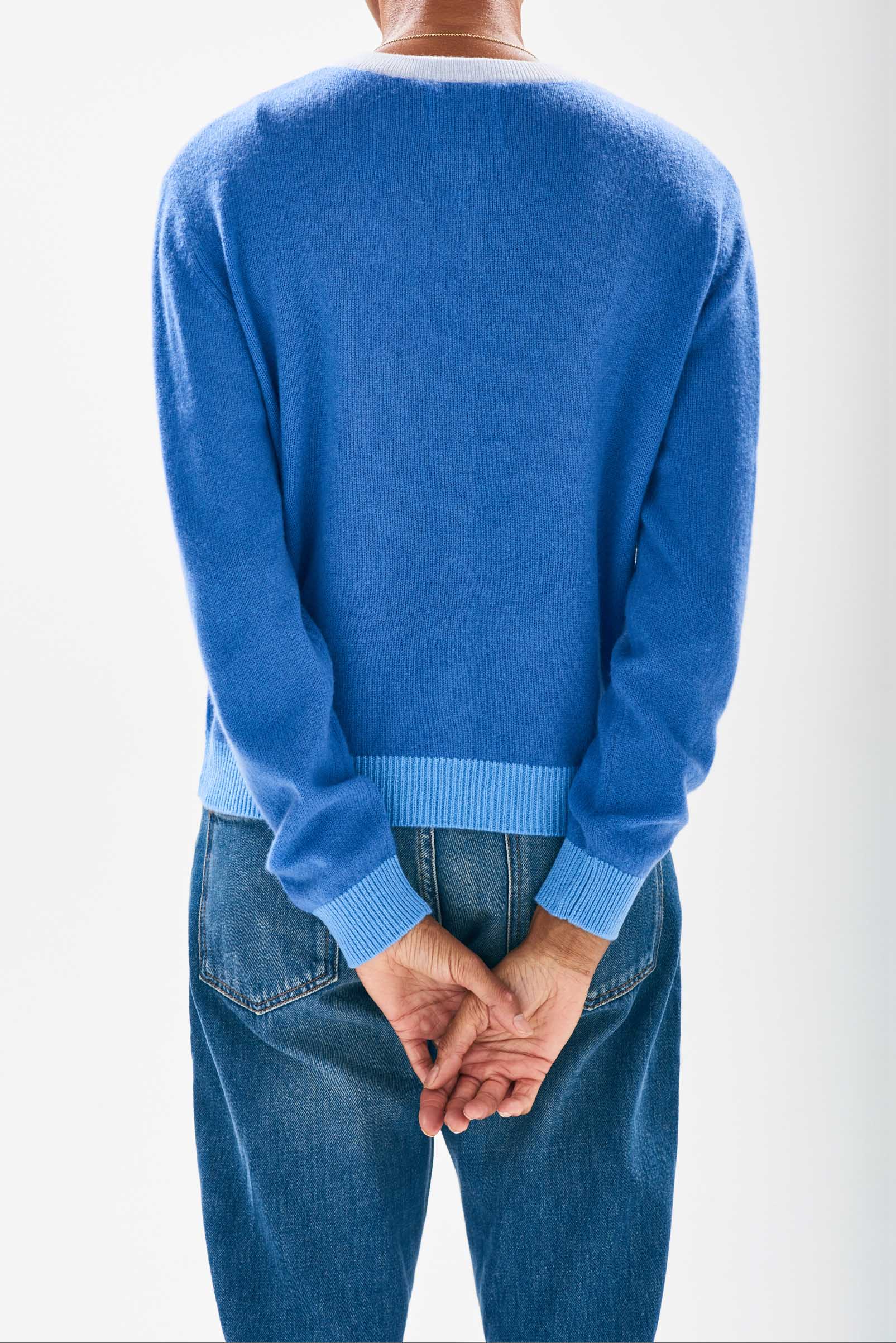 Model wearing Jumper1234 Cornflower blue cashmere cardigan with contrast ribs in pale blue and sky facing away from the camera