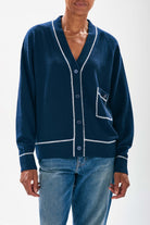 Model wearing Jumper1234 Navy boyfriend vee neck cashmere cardigan with cream top stitching detail and a pocket