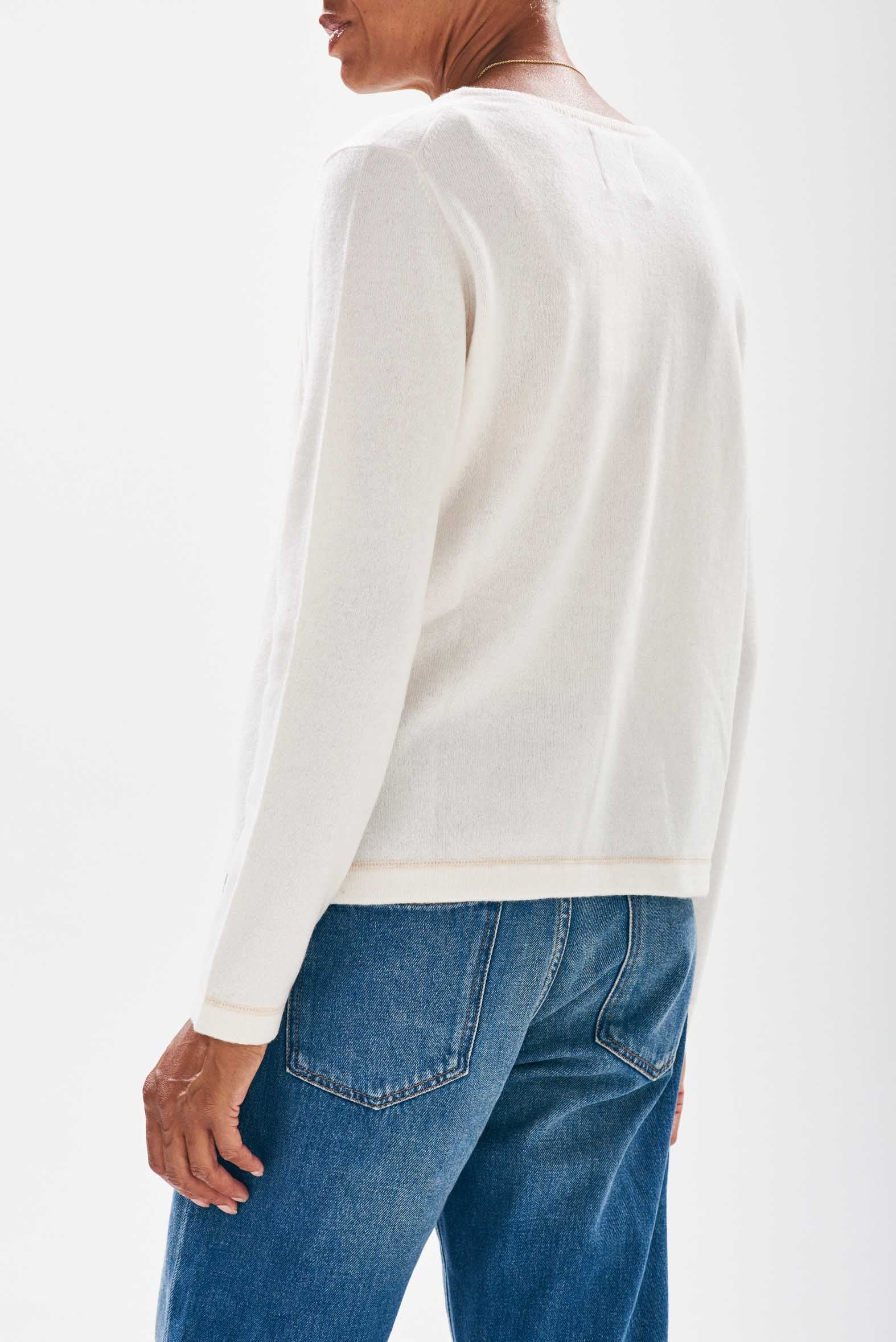 Model wearing Jumper1234 Cream cashmere crew neck jumper with organic light brown top stitching detail and a chest pocket facing away from the camera