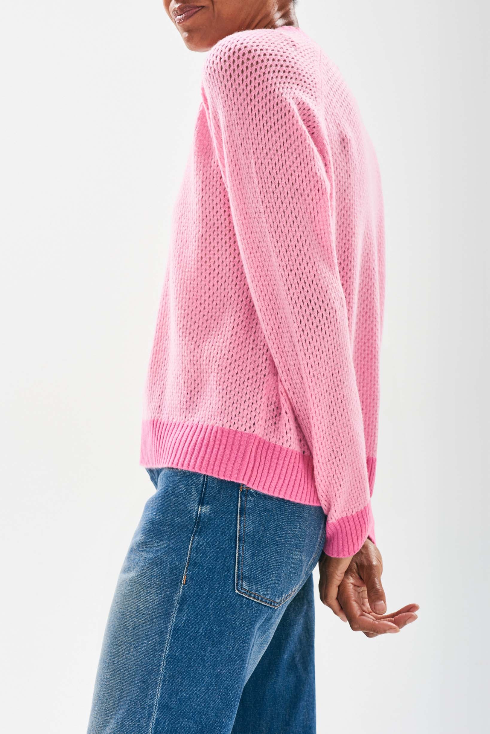 Model wearing Jumper1234 Mesh cashmere vee neck jumper in pink with contrast darker pink ribs facing away from the camera