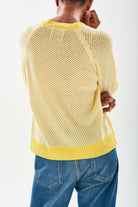 Model wearing Jumper1234 Mesh cashmere vee neck jumper in yellow with contrast darker yellow ribs facing away from the camera