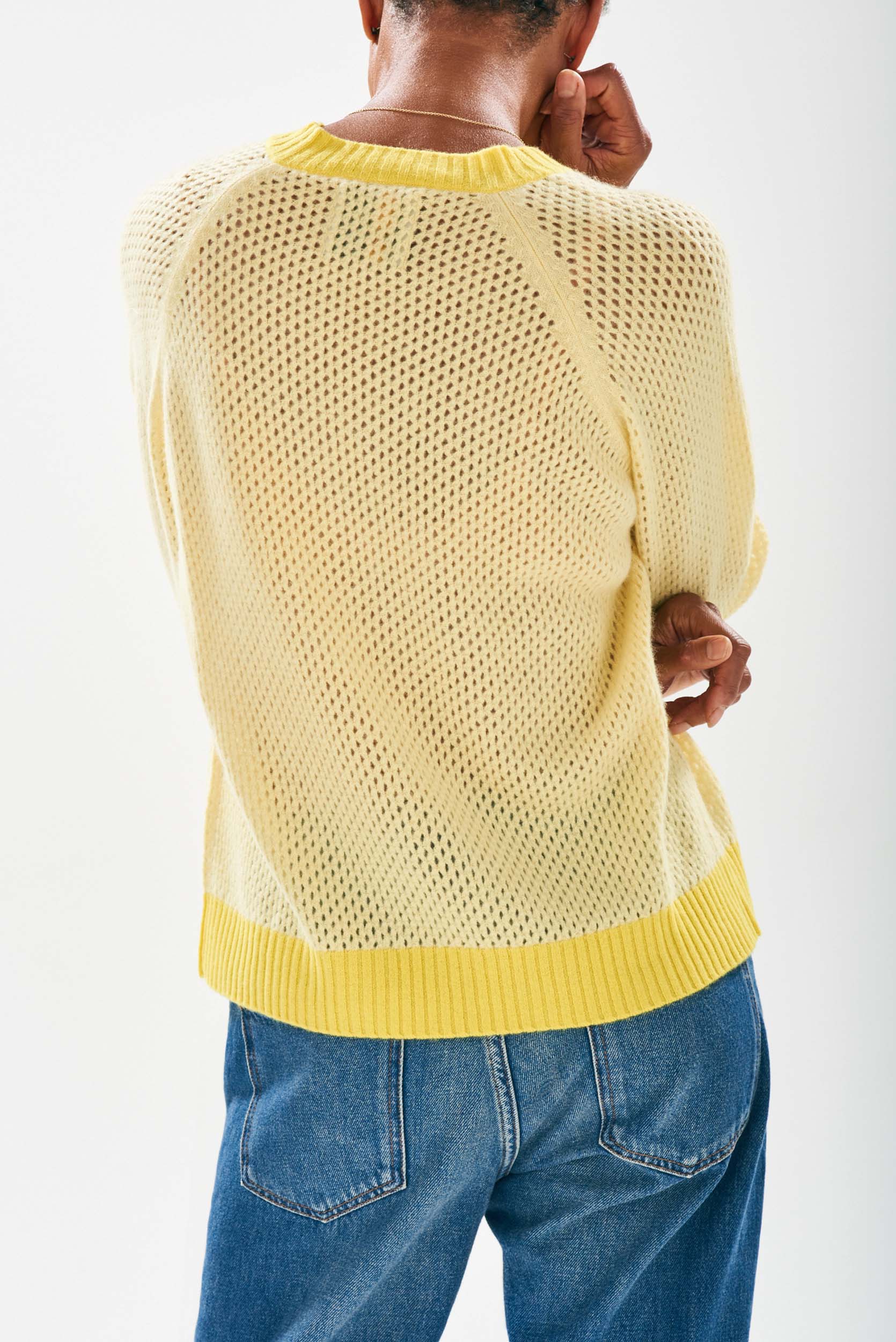 Model wearing Jumper1234 Mesh cashmere vee neck jumper in yellow with contrast darker yellow ribs facing away from the camera